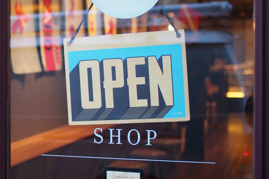 Open sign hanging on glass door at business shop